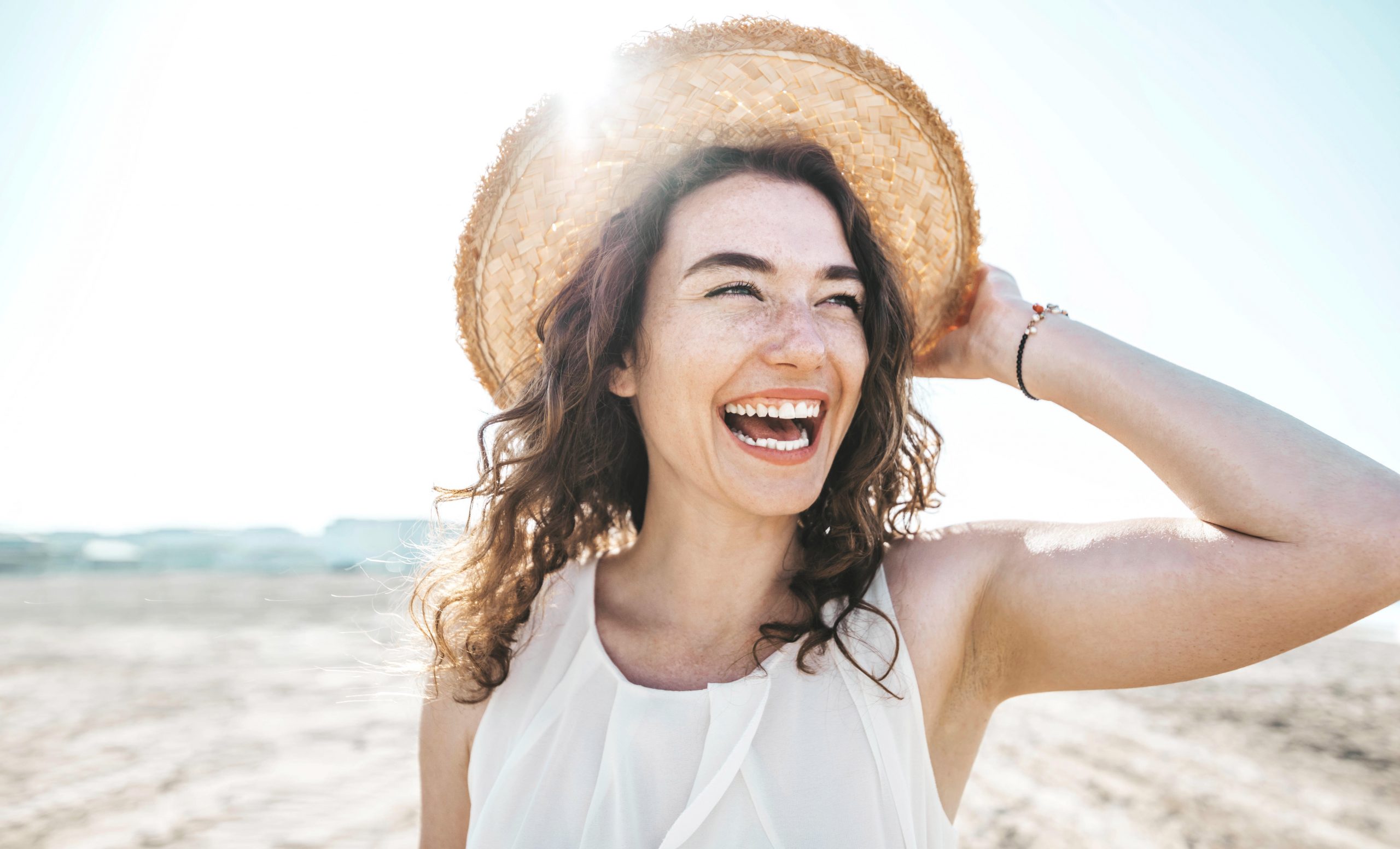 Happy woman smiling at the beach after learning about botox specials at Dr. Laurel Bailey Laser & Aesthetics